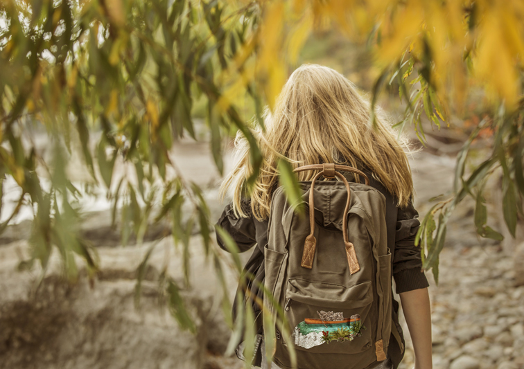 Eine Backpackerin mit einem Rucksack mit Print einer Illustration von Koalabären im Kanu